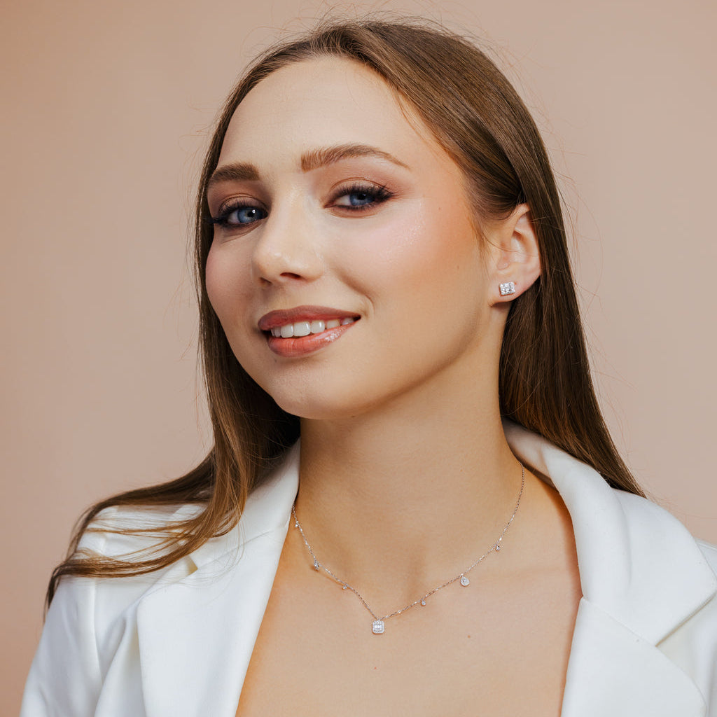 Woman wearing a white blazer and necklace against a beige background